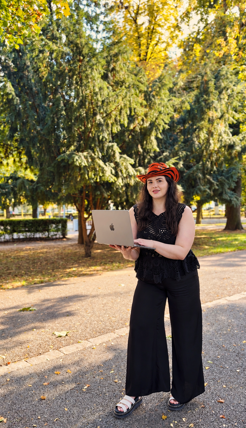 Andreea Chiș cu laptopul deschis în mână, în parc